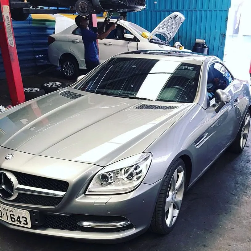 Veículos em manutenção na oficina Cristo Rei, com carro no elevador ao fundo